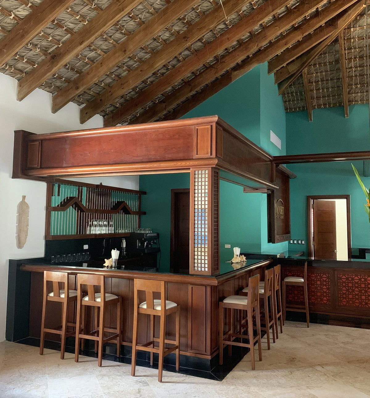 Pasillo con paredes en tono terracota, un banco de madera y plantas que se abre a un jardín
