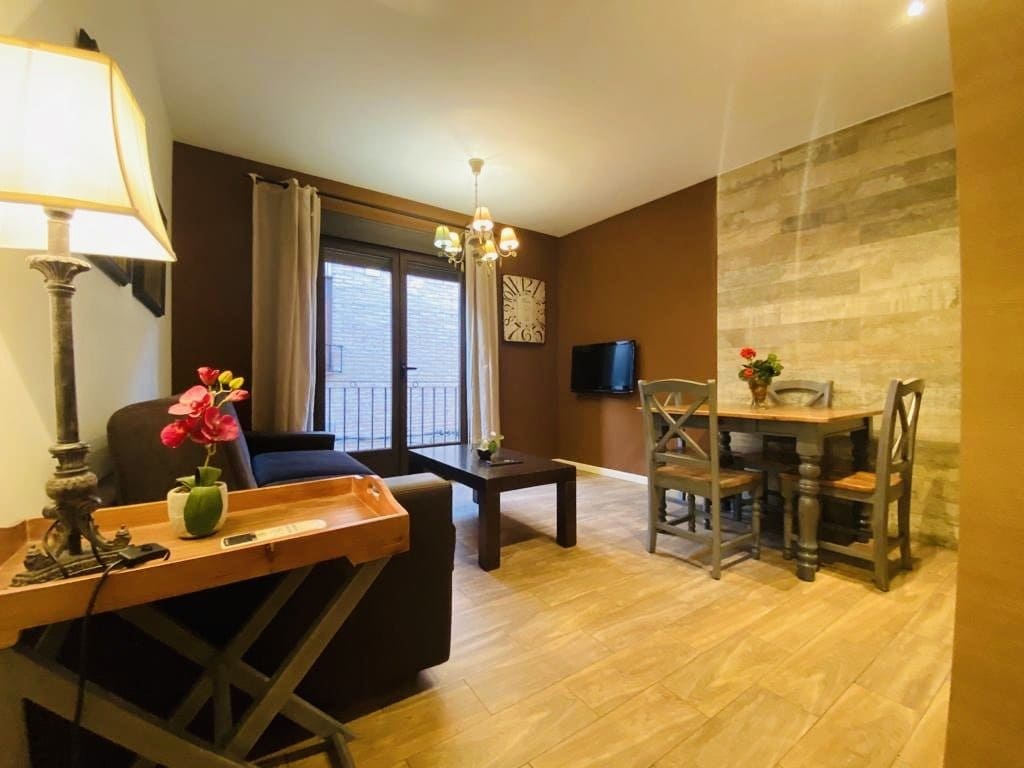 Salón con mesa de comedor, sofá, televisor y decoración rústica en tonos marrones