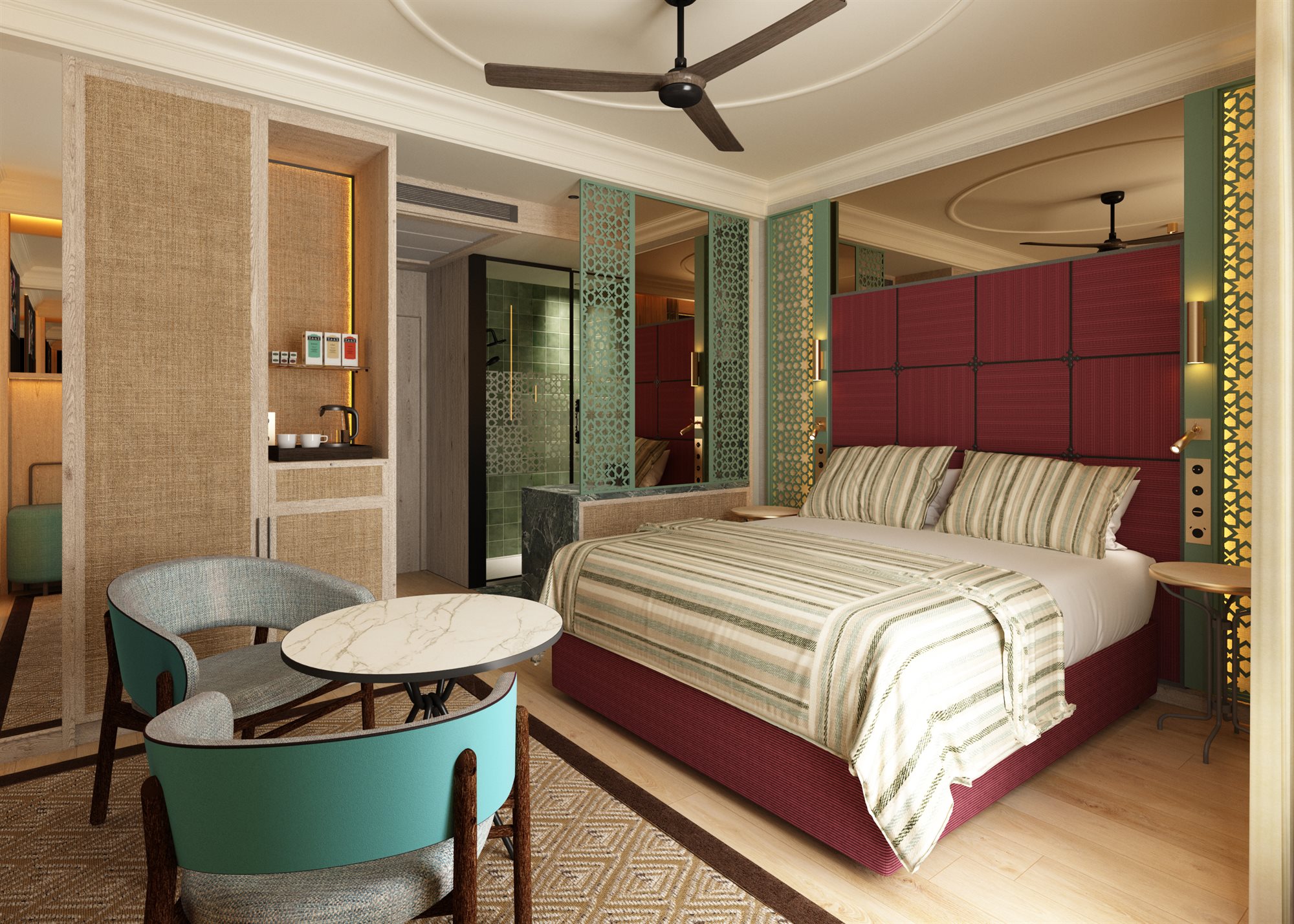 Habitación con cama de matrimonio, cabecero granate acolchado, colcha de rayas, ventilador de techo, butacas verde azulado con mesa redonda de mármol y celosías verdes caladas hacia el baño