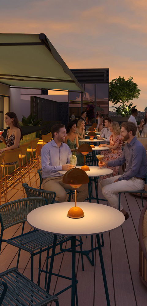 Terraza de la azotea con barra, comensales al atardecer y guirnaldas de luces