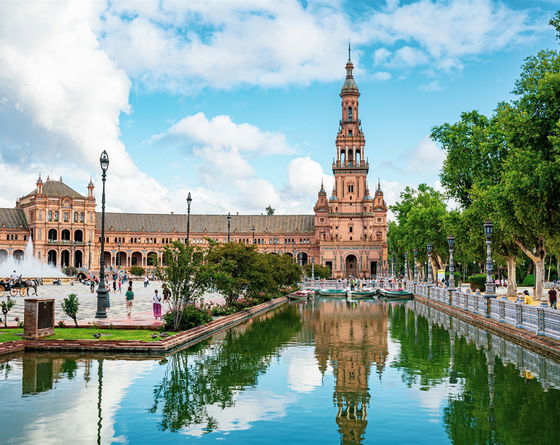 Torre de la Plaza de España de Sevilla vista desde el canal, con nubes y cielo despejado de fondo