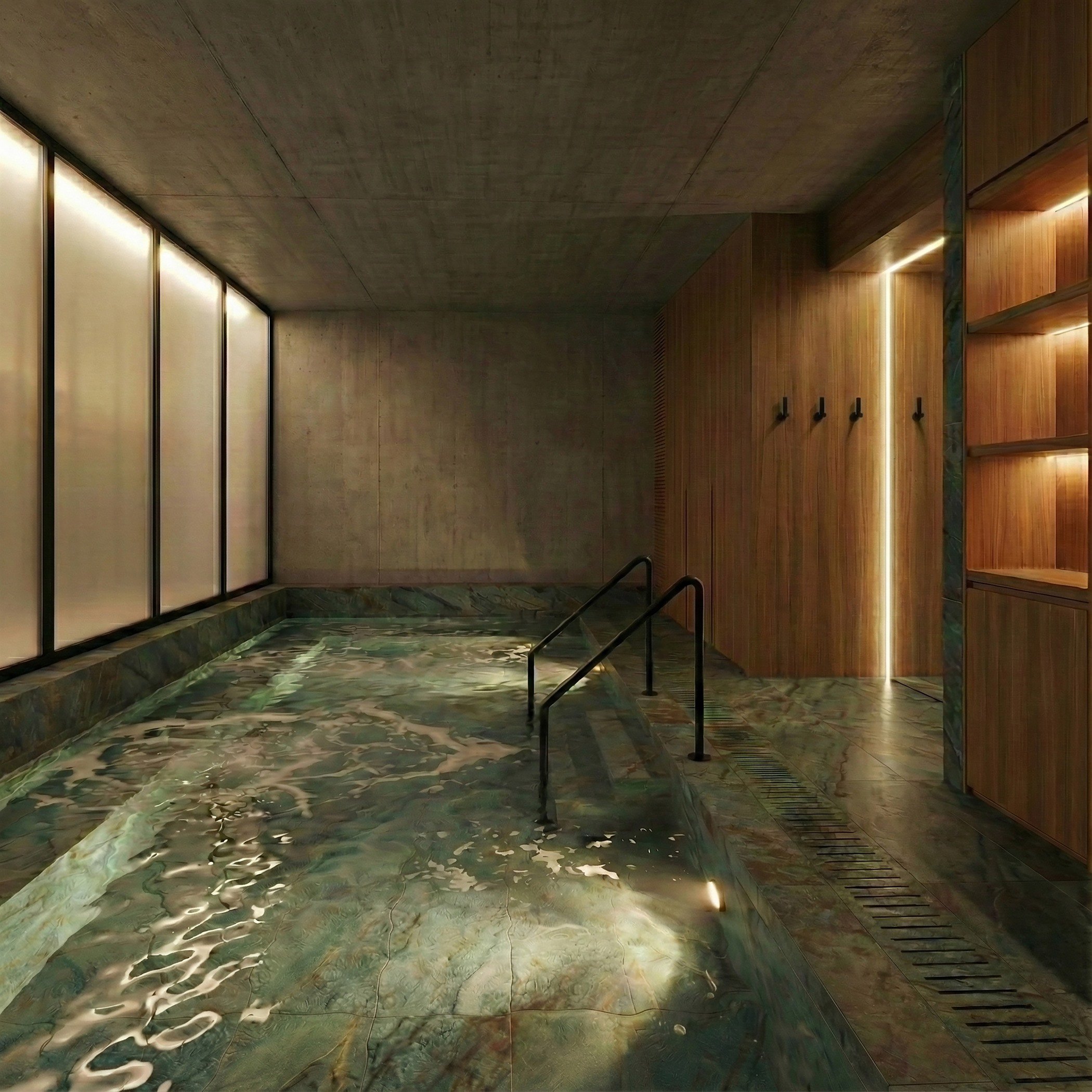 Piscina de inmersión en mármol verde con barandilla de acceso e iluminación tenue de spa