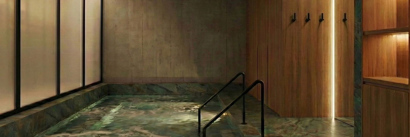 Piscina de inmersión en mármol verde con barandilla de acceso e iluminación tenue de spa