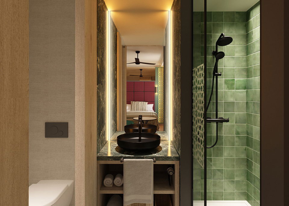 Baño en tonos oscuros con detalle de azulejo verde en la ducha